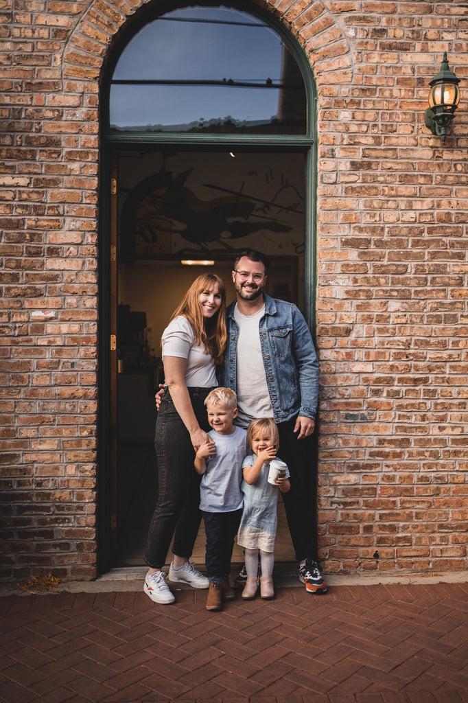 Five & Hoek owners Tyler, Beth and kids standing in front of our coffee shop and roasters located in Wheaton Illinois at 112B N Main St. Find us down the Alleyway for direct trade coffee, organic offerings and organic meal replacement smoothies! 